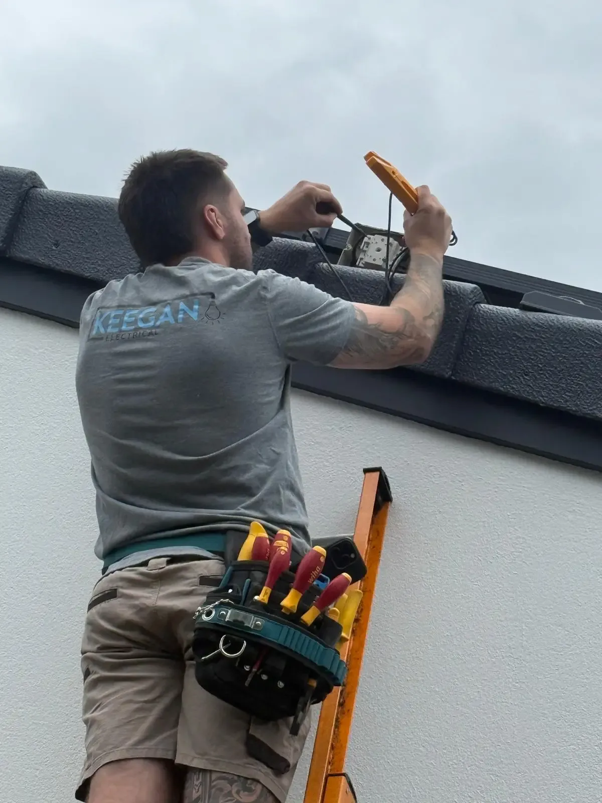 James Keegan working on an exterior wall fitting from a ladder