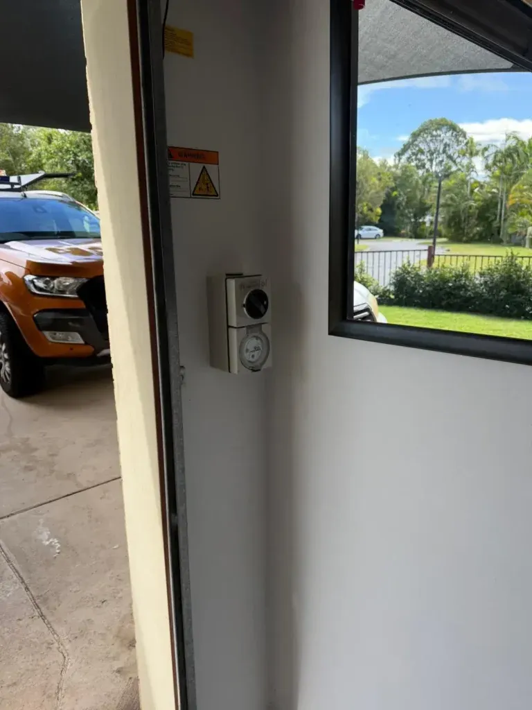 Wall-mounted home EV charger beside a garage window